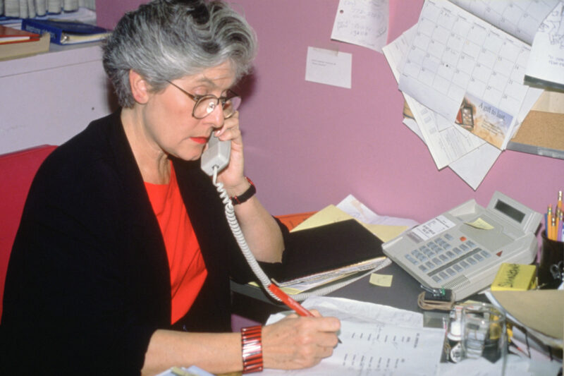 A woman with greying hair talks on a telephone
