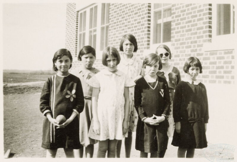 A group of girls stand outside next to a building.