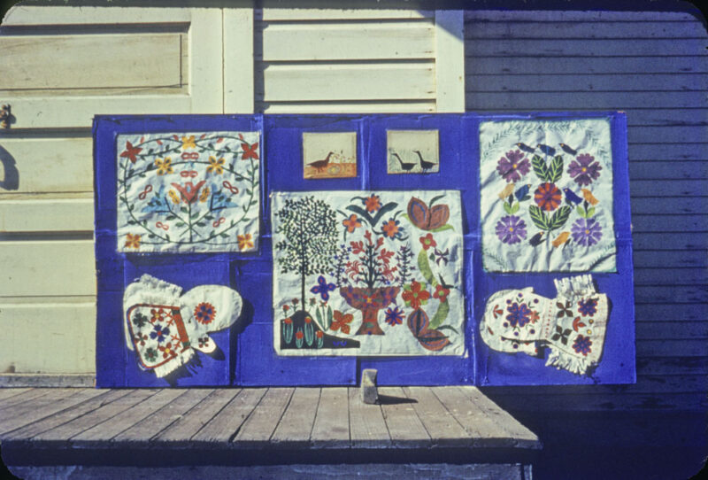 A collection of embroidered pieces mounted on a blue board.