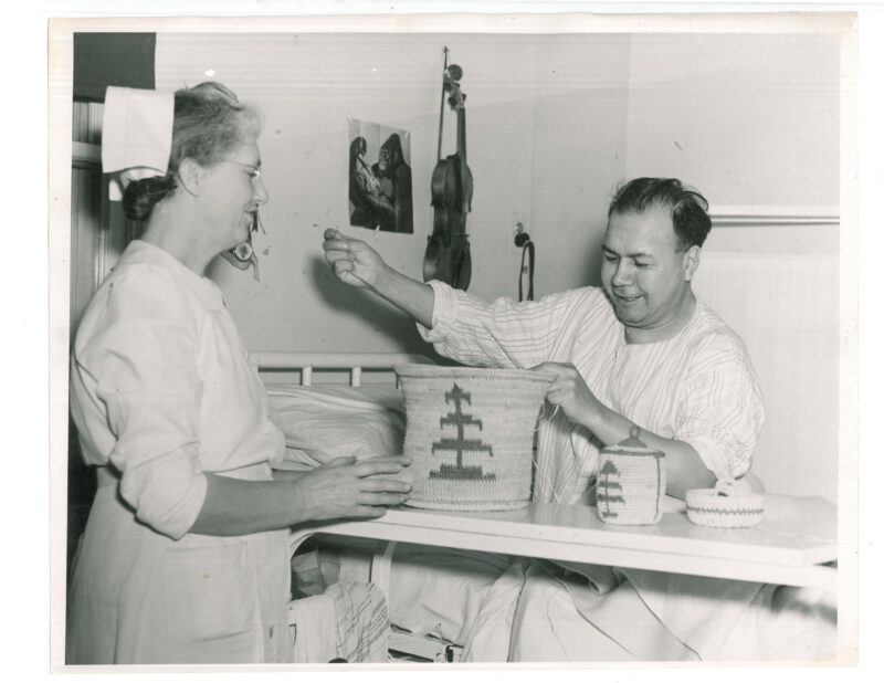 A male patient making baskets with a nurse watching. There is a violin on the wall next to him.