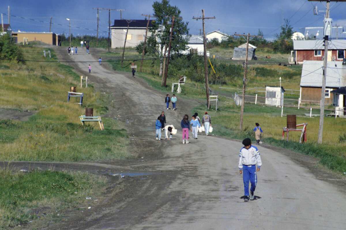 Landscape photo showing people walking along a road going up a hill.