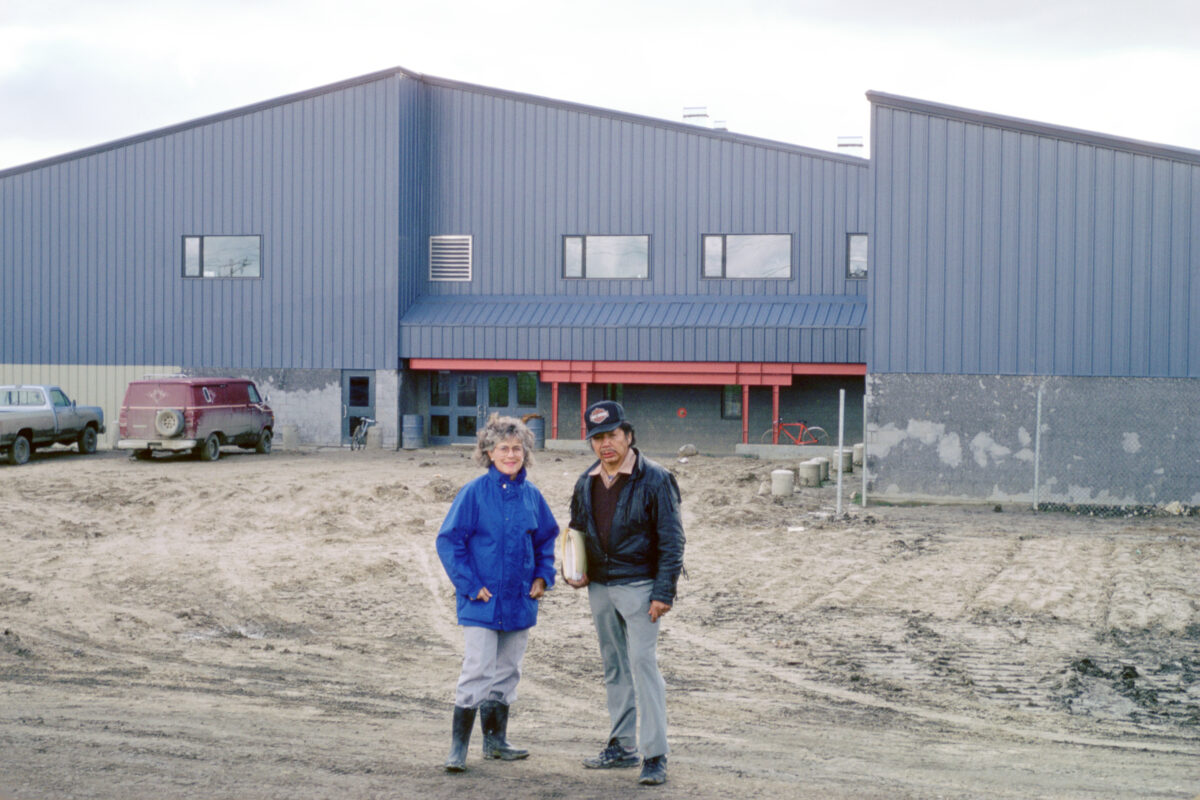 A man and woman standing outside of a blue building.