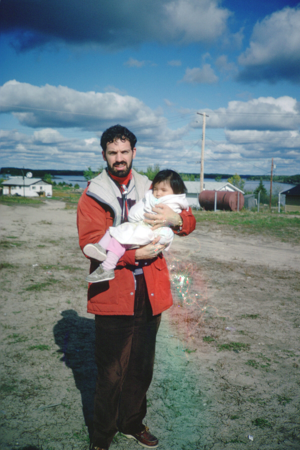 A man in a red jacket holding a small child.