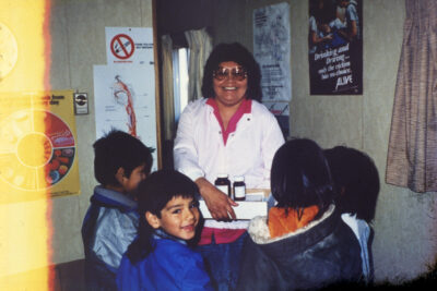 A woman holding a box containing medicine bottles, with four children around her.