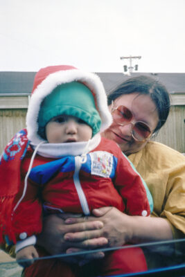 A woman holding an infant in a snowsuit.
