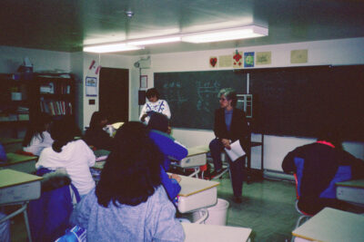 Two women at the front of a classroom full of students.