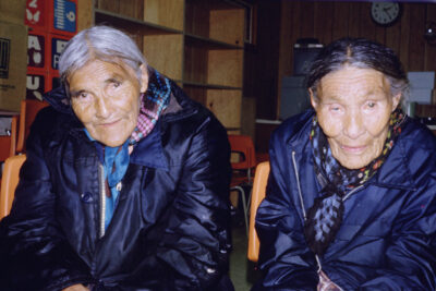 Two elderly people in dark jackets looking at the camera.