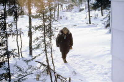 A woman in a black parka walks in the snow.