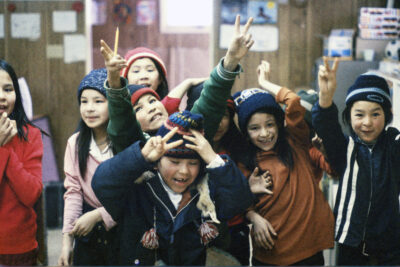A group of children making "peace" signs with their fingers.