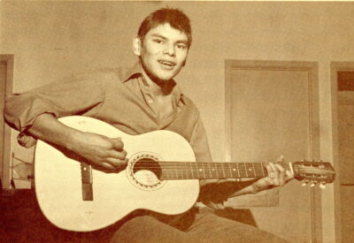 A young man strums a guitar.