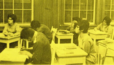 Young adults sit at classroom desks