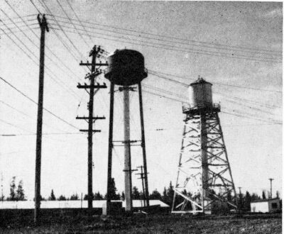 Two water tanks stand next to power lines.