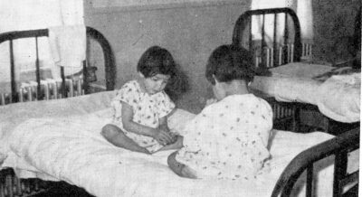 Two children play on a hospital bed.