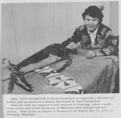 A woman sewing a bison hide robe.