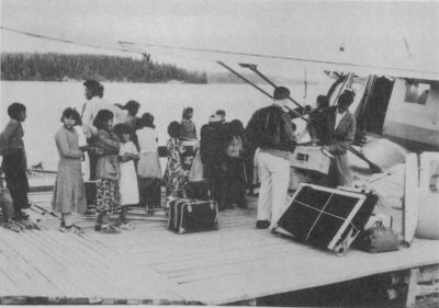 A group of people on a dock next to a sea plane.