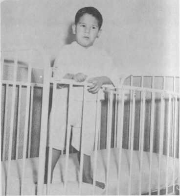 A young boy stands in a crib.
