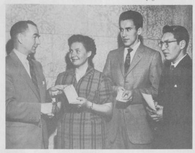 A man presents cheques to three young adults.