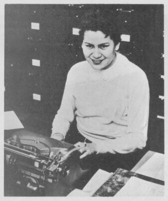 A woman sits at a typewriter.