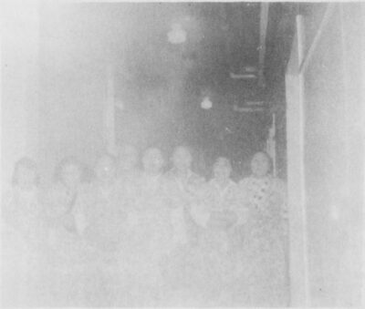 A group of women perhaps gathered in a hallway. (overexposed photo - hard to make out clearly)