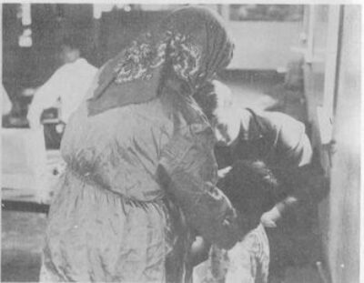 A woman wearing a head scarf and a man tend to a child.