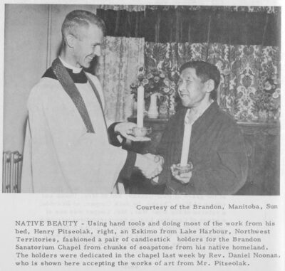 A reverend shakes hands with another man. Both men hold candles.