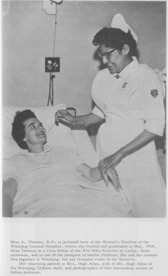 A nurse holds a patient's wrist while she inserts a thermometer into the patient's mouth.