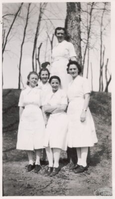 Five nurses stand outside next to a tree.