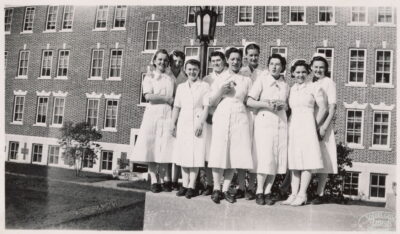 A group of nurses stand on a ledge in front of a building.