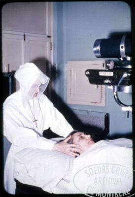 A nun holds the head of a woman lying below an x-ray machine.