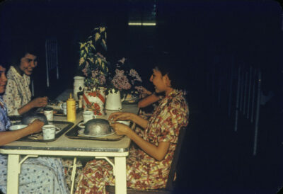 Young women smiling at a table with food trays in front of them.
