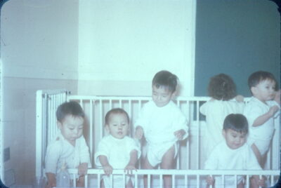 Six toddlers stand in a crib.
