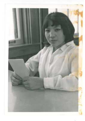 Young woman sitting at table holding a piece of paper
