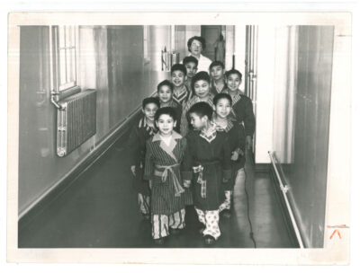 Ten male child patients in a hallway with nurse