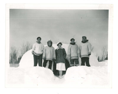 Four Inuit men and one female nurse outside in front of an igloo