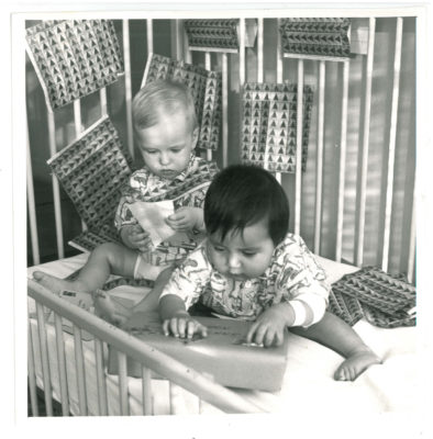 Two babies in a crib with Manitoba Lung Association Christmas seal stamps and a package