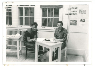Two men sitting at a table with books.
