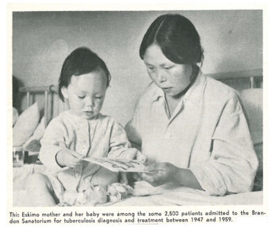 A woman and a young child sitting together in bed looking at a book. A printed caption reads: "This Eskimo mother and her baby were among the some 2,500 patients admitted to the Brandon Sanatorium for tuberculosis diagnosis and treatment between 1947 and 1959."