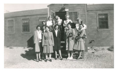 A group of women standing at the entrance of a building. Two women hold young children.