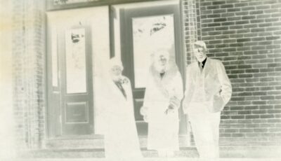 A negative showing three people at the entrance of a building.