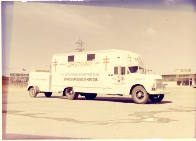 A Sanatorium Board of Manitoba mobile x-ray unit vehicle sits in the parking lot of a bakery.