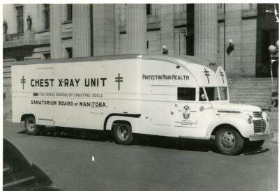 A Sanatorium Board of Manitoba mobile x-ray unit vehicle sits in front of a large building.
