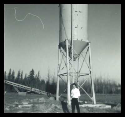 A man stands at the base of a silo.