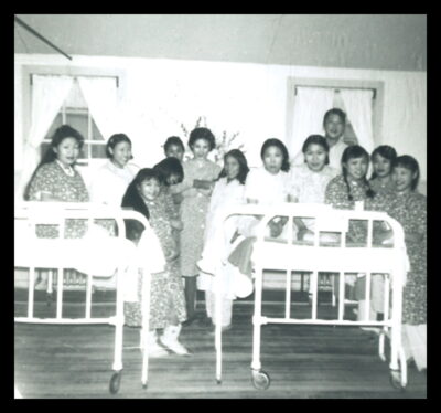 A group of women sitting on and standing next to hospital beds.