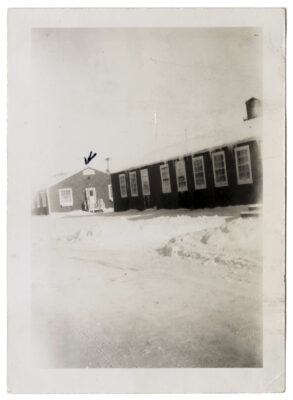 Two buildings.  A handwritten arrow is pointing to the staff quarters at the Clearwater Lake Indian Hospital. Snow is on ground and icicles hang from the roofs.